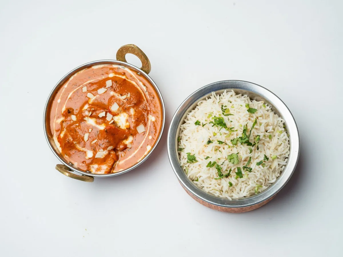 Butter Chicken in einer Kupferschale mit Sahne und Koriander